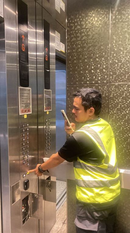 Juruteknik menguji butang panel operasi kabin lif
